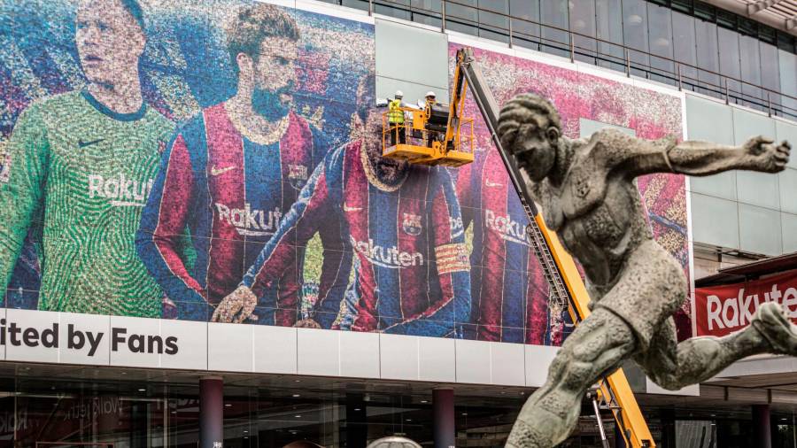 ADIÓS Operarios retirando un cartel de Messi en la fachada del Camp Nou de Barcelona. Foto: DPA Europa Press