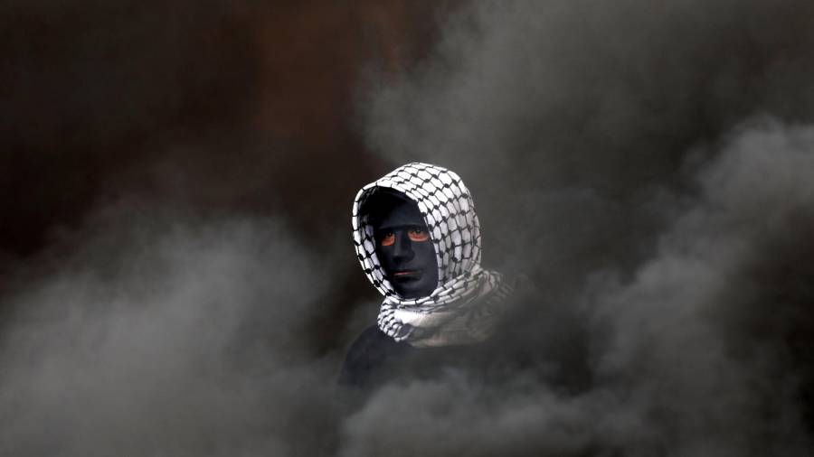 Una cabeza con máscara emerge a través del humo. La figura resalta gracias a la palestina blanca que lleva puesta. Pertenece a un miembro de la tribu bereber Hawwara en Argelia. (Autor, Alaa Badarneh. Fuente, EFE)