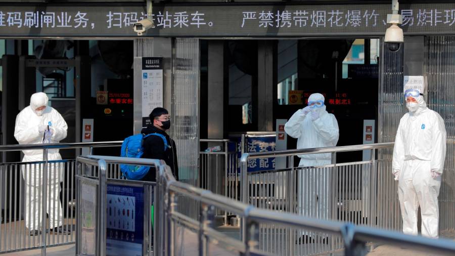 Foto de archivo de miembros de seguridad protegidos con trajes aislantes esperando a la entrada del metro para tomar la temperatura a los pasajeros en Pekín. Foto: EFE/ Wu Hong