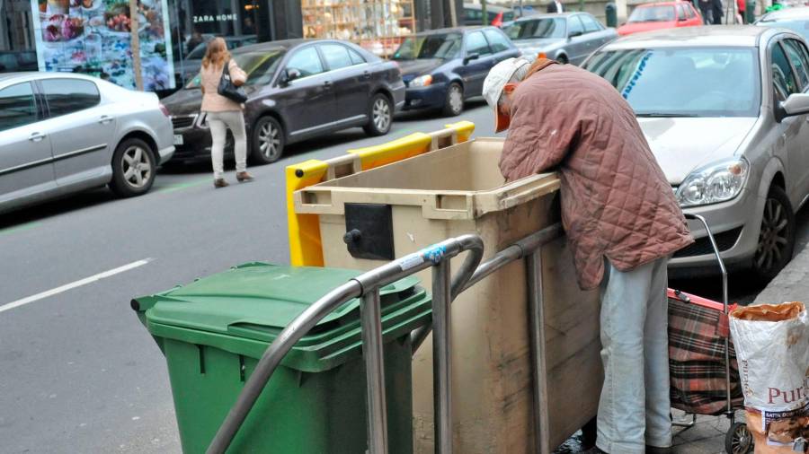 CRISIS. Una persona en riesgo de exclusión rebusca en un contenedor en una calle de la capital coruñesa Foto: Almara 