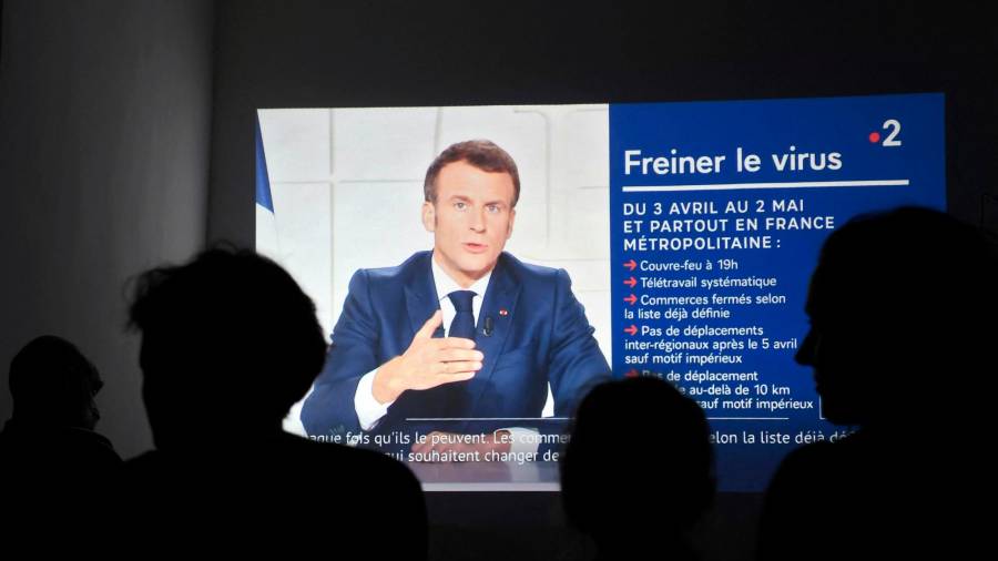 Un grupo de ciudadanos siguen por televisión la intervención, este miércoles, del presidente francés, Emmanuel Macron Foto: E.P.