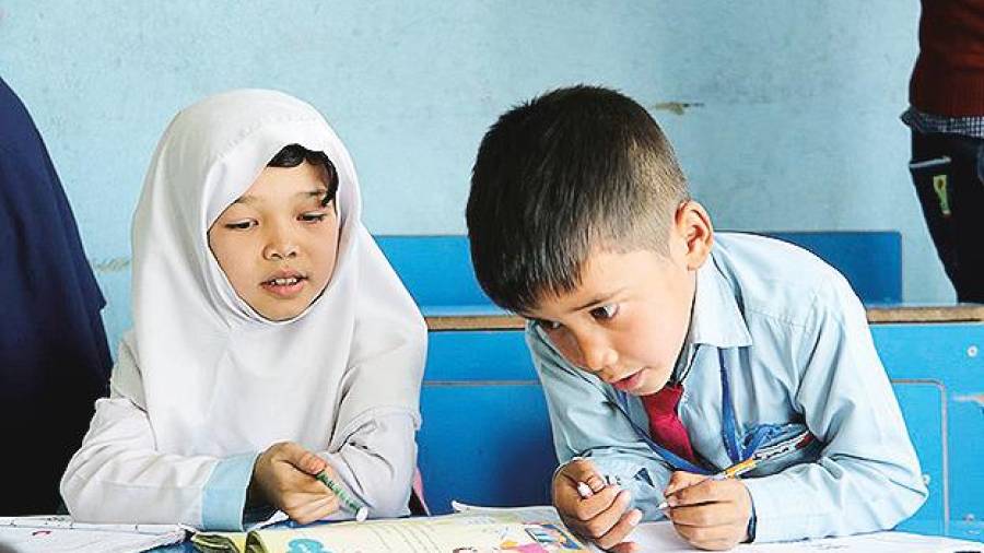 Dos niños hazara realizan sus tareas en una escuela