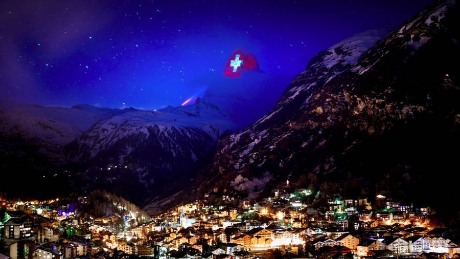 La montaña de Matterhom, en Zermatt, iluminada con la bandera de Suiza como símbolo de solidarización con la gente que ha sufrido por culpa de la pandemia causada por el covid-19. (Autor, Valentin Flauraud para EFE).
