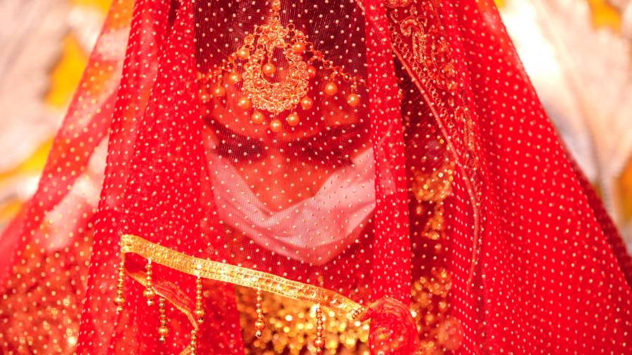Bajo el velo puede apreciarse como la novia lleva puesta la mascarilla. (Autor, Sanjeev Gupta. Fuente, EFE)