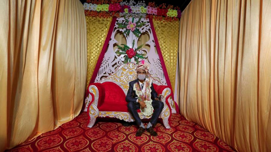 Ashish espera la llegada de la novia con la mascarilla puesta en el Mandap, una tienda decorada con flores, guirnaldas y alfombras donde se celebrará la boda. (Autor, Sanjeev Gupta. Fuente, EFE)