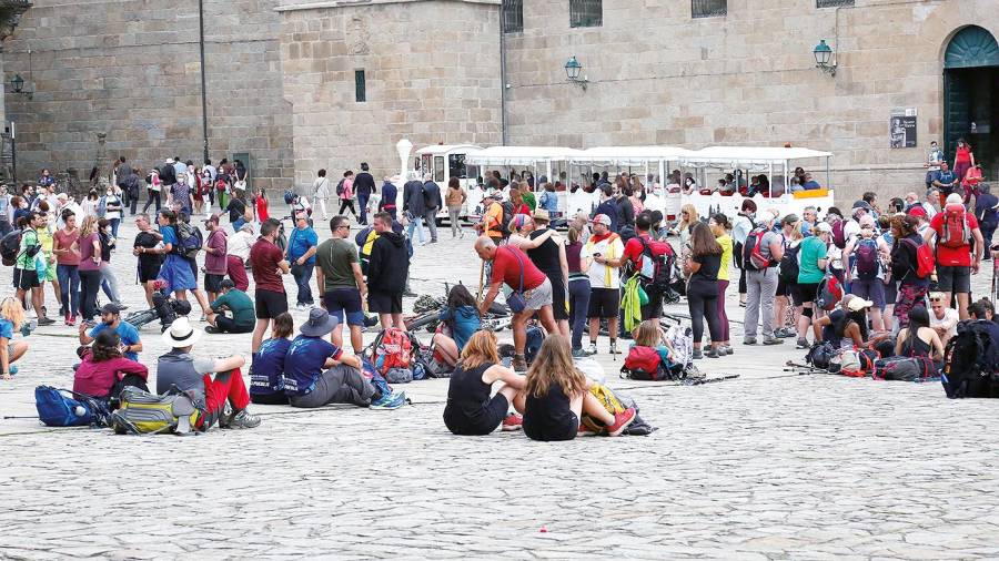 Numerosos turistas y peregrinos disfrutando, ayer, de la majestuosidad de la plaza del Obradoiro. Fotos: Antonio Hernández