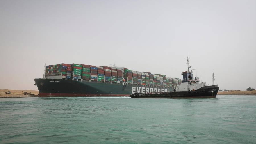 25 de marzo de 2021, Egipto, Suez: Un remolcador pasa junto al “Ever Given”, un buque portacontenedores operado por Evergreen Marine Corporation, que actualmente se encuentra atascado en el Canal de Suez. La estatal Autoridad del Canal de Suez (SCA) anunció el jueves que la navegación por el Canal de Suez ha sido suspendida temporalmente hasta la reflotamiento completo del superpetrolero panameño que encalló el martes en el extremo sur del Canal de Suez y bloqueó el tráfico en ambos. direcciones. El barco giró de costado en el Canal, mientras se dirigía de China a Rotterdam, debido a la visibilidad reducida que resultó de una tormenta de polvo que azotó el área, según SCA. Foto: - / Autoridad del Canal de Suez / dpa