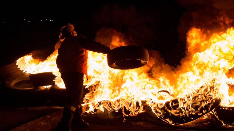 Un trabajador quema neumáticos durante la huelga general para reivindicar un futuro para la comarca, a 17 de noviembre de 2021, en A Mariña, Lugo, Galicia, (España). Con esta huelga, reclaman “medidas inmediatas” por parte de la Administración, para frenar “la pobreza, la desertización industrial y el despoblamiento”. La Confederación Intersindical Galega, CCCOO y UGT han comunicado que la convocatoria de huelga general va a afectar a todas las actividades desempeñadas por el personal de empresas privadas y del sector público, desde las 00:00 horas hasta las 24:00 horas de este 17 de noviembre. La Xunta por su parte ha establecido servicios mínimos en algunos sectores. / Carlos Castro / Europa Press 16/11/2021