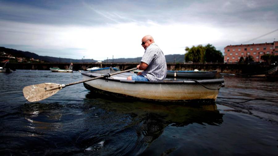 DE PESCA. Un hombre sale a pescar ayer en su bote auxiliar, fondeado en el puerto de Pontedeume. Foto: EFE / Cabalar