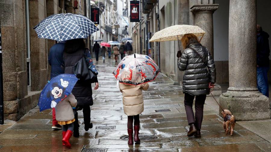 temporal. Gente paseando ayer por Santiago con el paraguas como complemento imprescindible en toda Galicia, jornada con frío aunque menos que el sábado. Foto: A. Hernández