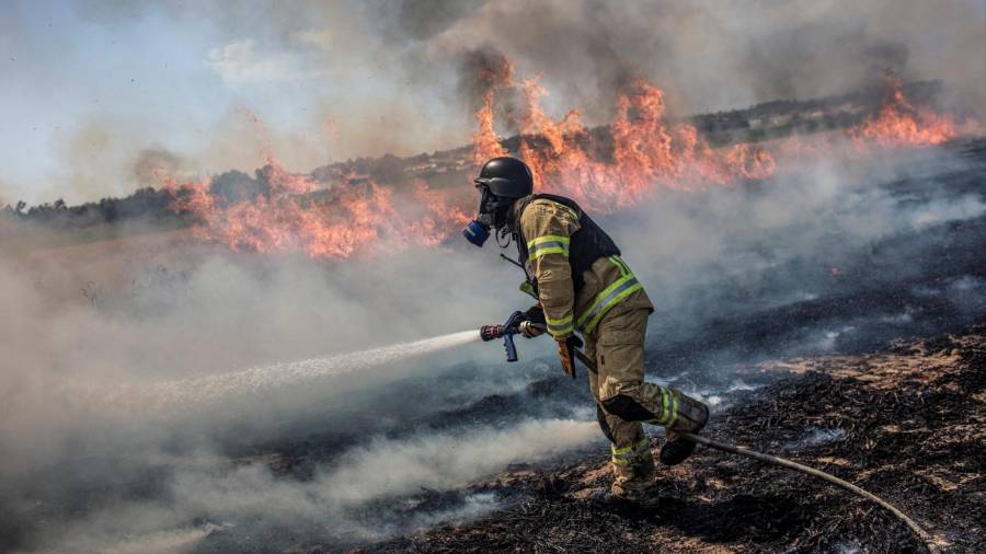 16 de maio de 2021, Israel, Ashkelon: un bombeiro israelí loita contra un incendio nun campo provocado por un foguete lanzado desde a Franxa de Gaza cara a Israel, no medio da escalada de violencia israelí-palestina. Foto: Ilia Yefimovich / dpa