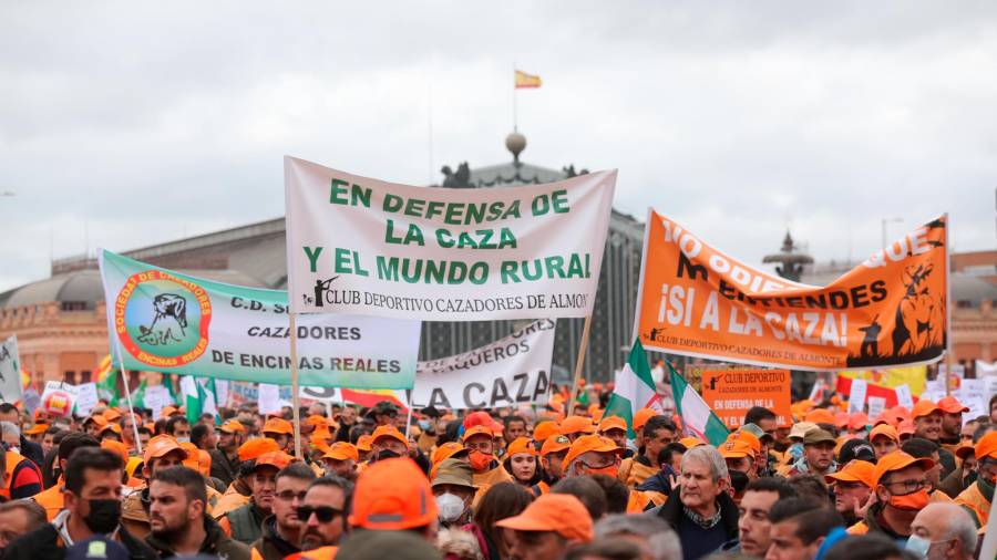 Varios manifestantes, con gorras naranjas y pancartas en defensa de la caza, en la marcha ‘20M’, a 20 de marzo de 2022, en Madrid (España). Los organizadores de esta convocatoria, denominada como ‘20M’, son Asaja, COAG, UPA, Real Federación Española de Caza (RFEC), Oficina Nacional de la Caza (ONC), Alianza Rural, Unión de Criadores del Toro de Lidia (UCTL), Federación Nacional de Comunidades de Regantes de España (Fenacore) y Cooperativas Agro-alimentarias. Esta multitudinaria marcha reivindica un futuro mejor para el mundo rural y las actividades que lo sustentan. // Isabel Infantes / Europa Press 20/03/2022