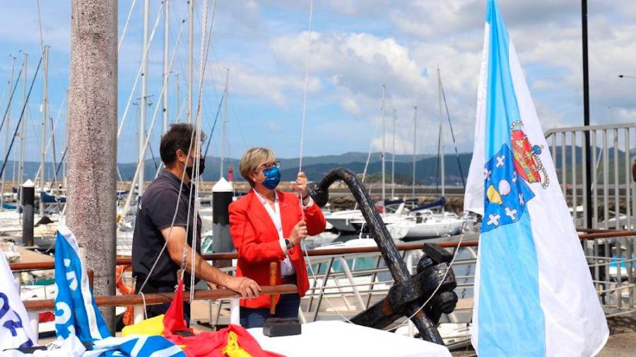 Rosa Quintana izando a bandeira de Galicia, a azul e a da Q de Calidade no Náutico de Portosín. Foto: Xunta