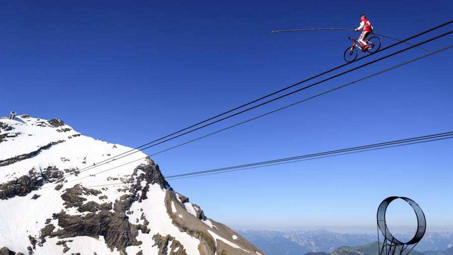El funambulista Freddy Nock recorre 367 metros en bicicleta por el cable del teleférico en el suizo Glacier 3000 en Les Diablerets. (Autor, Laurent Gilleron. Fuente, EFE.)