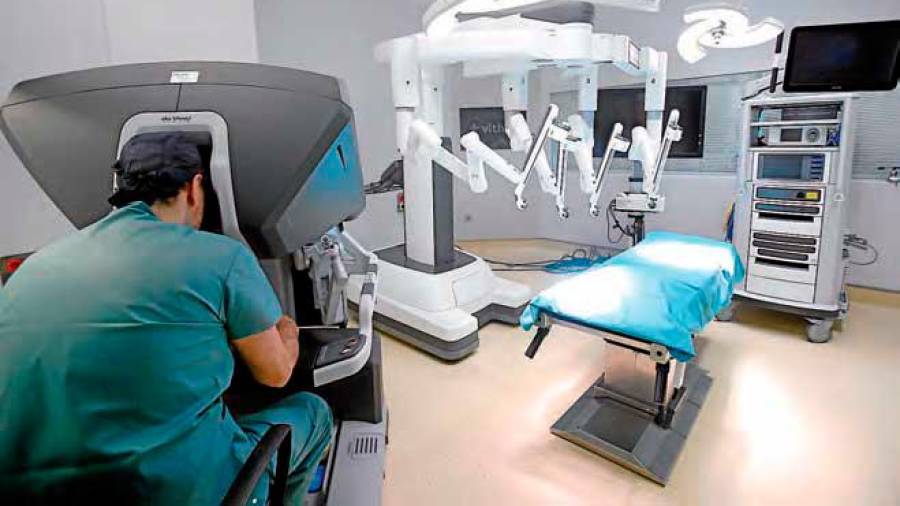 El doctor Fernando Santos en la consola del robot Da Vinci, desde donde se realiza la intervención quirúrgica, mientras otro especialista controla los brazos del instrumento. FOTO: Fernando Blanco