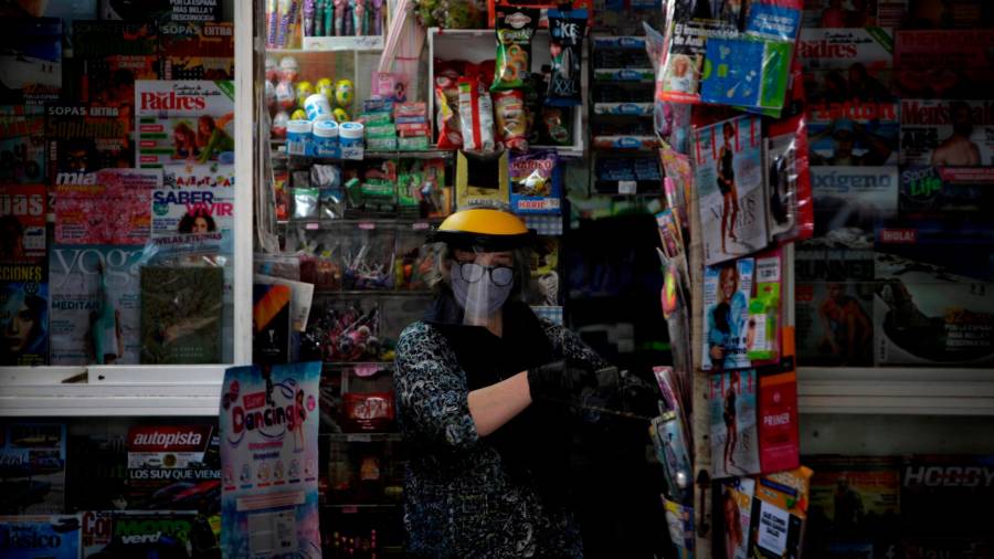 A CORUÑA, 22/05/2020.- Una mujer protegida con pantalla y mascarilla, atiende este viernes un kiosko de prensa en A Coruña. EFE/Cabalar
