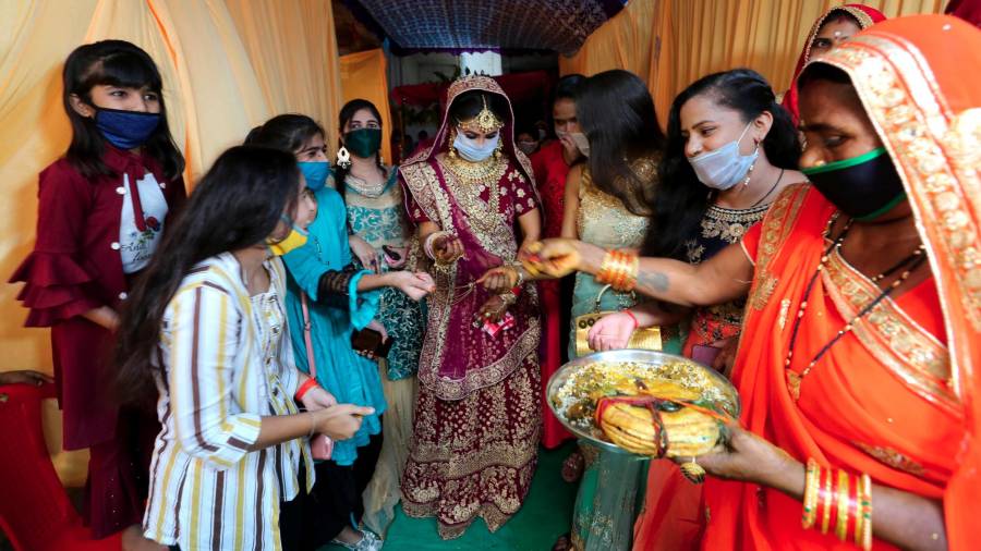 Camino a la ceremonia, Bride y sus acompañantes van cubiertas con mascarillas para evitar contagios. (Autor, Sanjeev Gupta. Fuente, EFE)