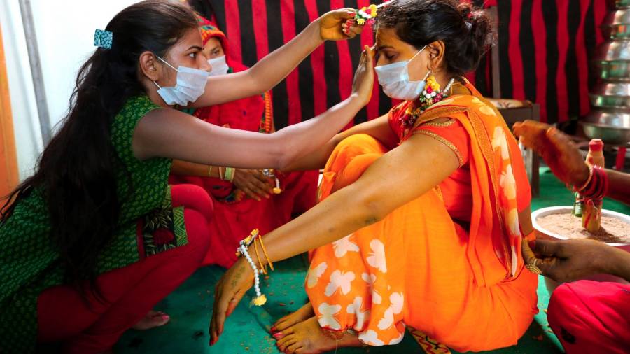 La hermana de Bride le ayuda a preparar el peinado, ambas con la mascarilla puesta. (Autor, Sanjeev Gupta. Fuente, EFE)