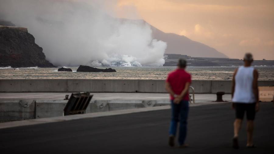 Dos personas observan la columna de humo y la lava del volcán de Cumbre Vieja a su llegada al Océano . Foto: Europa Press 