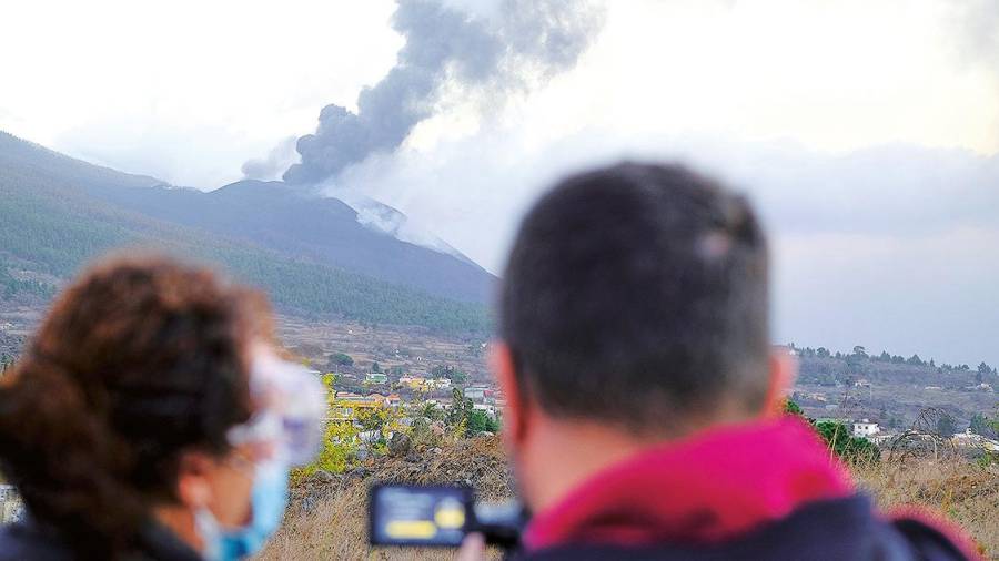 Dos personas observan la columna de humo procedente de la erupción volcánica. Foto: E.P.