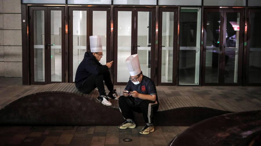 Dos cocineros consultan el móvil en el exterior de un centro comercial en Beijing (China). EFE/EPA/WU HONG