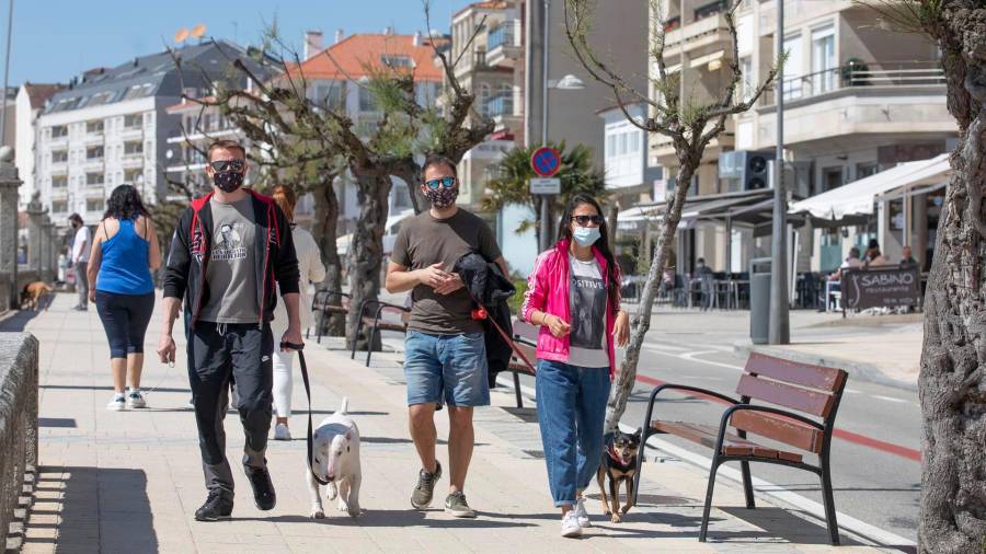 EN SANXENXO. Varias personas caminan por el paseo marítimo portando sus correspondientes mascarillas . Foto: Beatriz Ciscar/E.P.