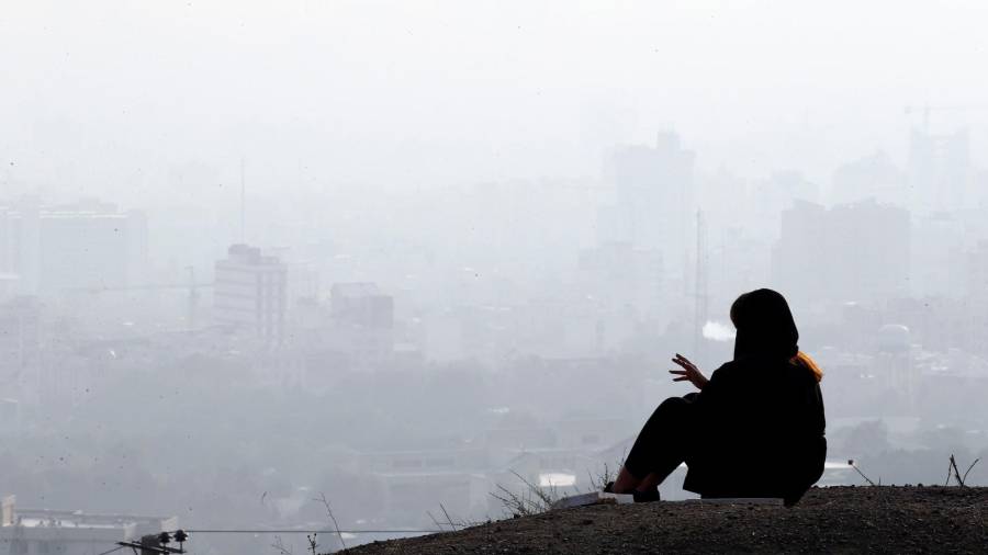 Una adolescente iraní fuma mientras ve la ciudad de Teherán bajo la niebla tóxica. Efe