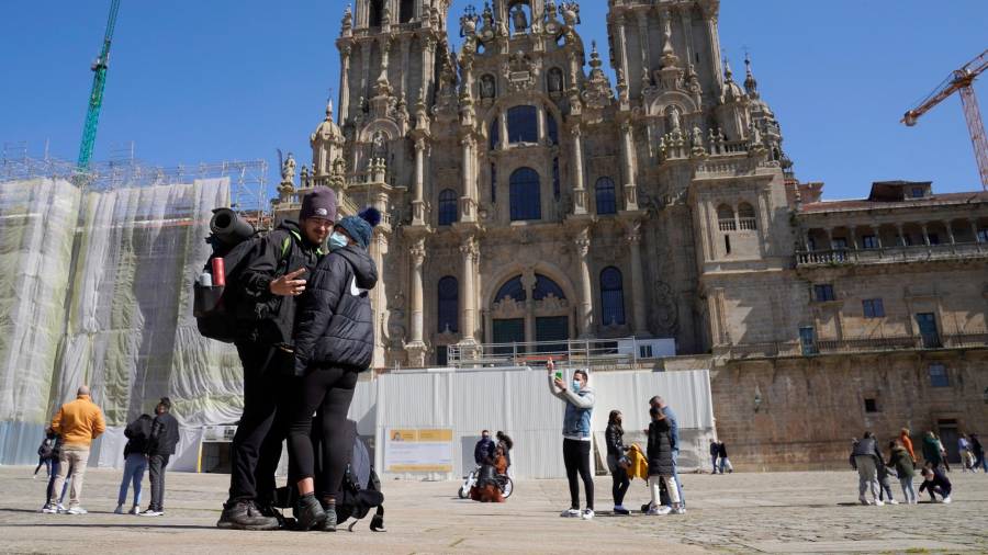 Una pareja de peregrinos se fotografía con la Catedral de fondo. Foto: Álvaro Ballesteros/Europa Press