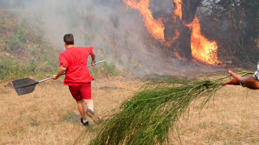 folgoso do courel. Una persona ayuda a apagar el fuego para que no llegue a su casa. Foto: Carlos Castro