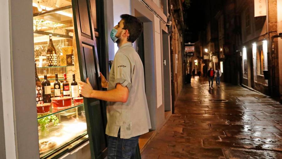 Un camarero protege su establecimiento a la hora del cierre por las medidas ordenadas por la crisis. FOTO: Álvaro Ballesteros