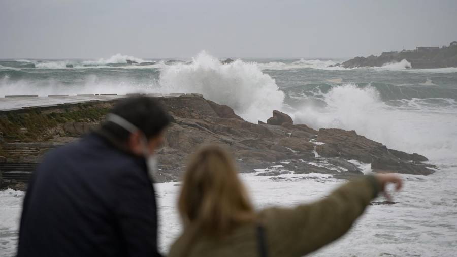Dos personas observan el fuerte oleaje en la costa en A Coruña, a 8 de enero de 2022, en A Coruña, Galicia, (España). La Agencia Estatal de Meteorología activó un aviso naranja que ha ampliado hasta el 10 de enero en todo el litoral gallego por viento y olas que podrían ascender hasta los 7 metros. Las playas permanecerán cerradas hasta el martes 10 de enero. Las olas que golpean con fuerza la costa se han originado en Groenlandia, a más de 3.700 kilómetros, donde hay una borrasca explosiva con una presión muy baja. / M. Dylan / Europa Press 08/01/2022