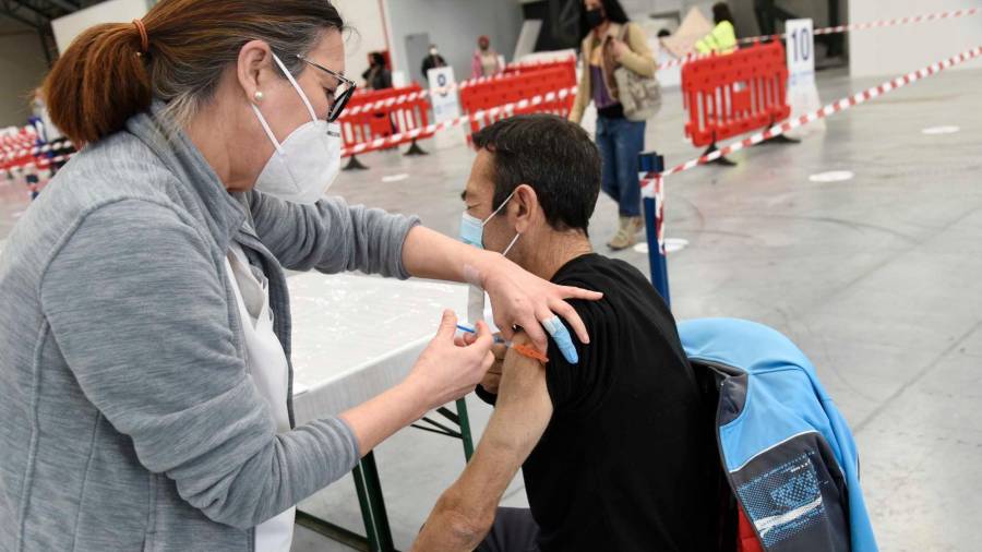 Una sanitaria vacuna a una hombre en el Instituto Ferial de Vigo (Ifevi), en Pontevedra, Galicia (España), a 13 de marzo de 2021. Un total de 4.400 personas serán inmunizadas por un equipo de 60 profesionales sanitarios que administrarán la vacuna de AstraZeneca a los ciudadanos de entre 50 y 55 años desde las 8 de la mañana hasta las 22 horas. Estas personas han sido notificadas por SMS al teléfono móvil y después una máquina ha realizado una llamada de confirmación de la asistencia. La vacunación masiva que ha sido programada por el Servizo Galego de Saúde será una prueba piloto repetida en otros puntos de la región. Europa Press 13/03/2021