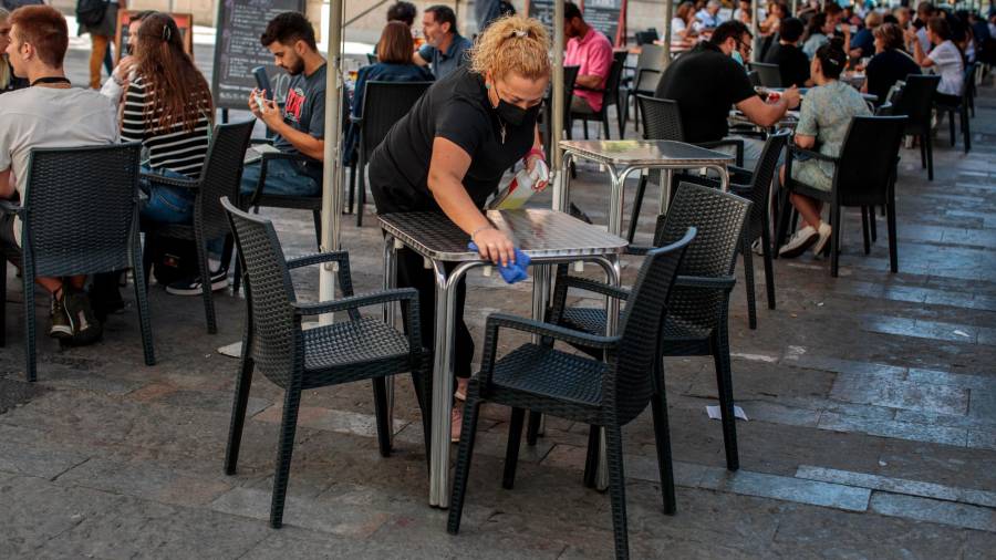 Una camarera desinfecta una mesa en una terraza de la capital valenciana. Foto: Biel Aliño/Efe
