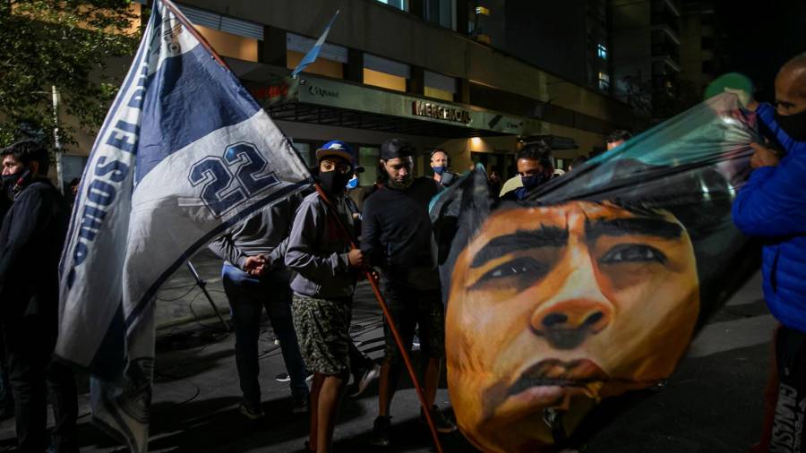 Seguidores del exfutbolista argentino Diego Maradona sostienen una pancarta con su imagen afuera de la clínica Ipensa, en La Plata (Argentina), donde fue operado. EFE/Demian Alday Estévez