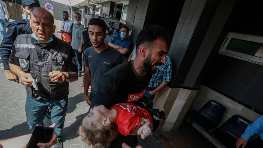16 de maio de 2021, Territorios palestinos, cidade de Gaza: un home leva o corpo dun neno palestino, que foi asasinado nun ataque aéreo israelí, fóra da morgue do hospital Al-Shifa, no medio do intenso estalido da violencia israelí-palestina. Foto: Mohammed Talatene / dpa