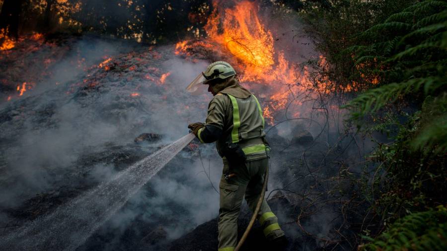 GRAF9829. TOÉN (OURENSE), 07/08/2020.- Un bombero realiza labores de extinción en el incendio forestal que permanece activo en el municipio orensano de Toén. EFE/Brais Lorenzo