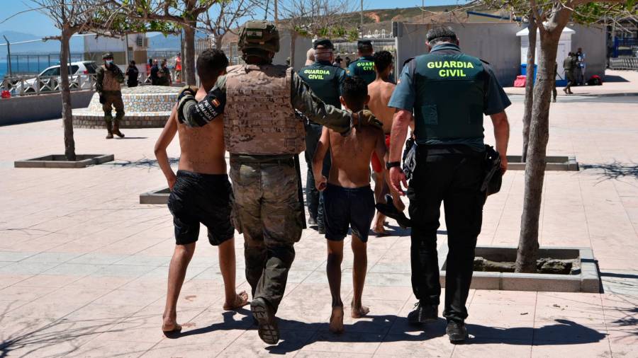 Un militar y un guardia civil ayudan a dos menores migrantes en Ceuta. Foto: Antonio Sempere/E.P.
