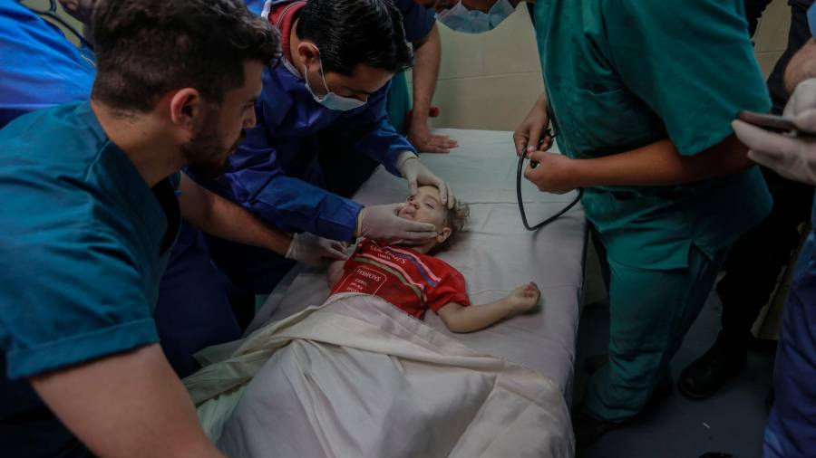 16 de maio de 2021, Territorios palestinos, cidade de Gaza: os traballadores sanitarios inspeccionan o corpo dun neno palestino, asasinado nun ataque aéreo israelí, dentro da morgue do hospital Al-Shifa no medio do intenso estalido da violencia israelí-palestina. Foto: Mohammed Talatene / dpa