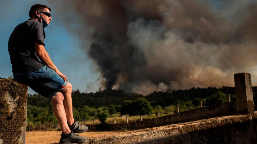 GRAF9833. TOÉN (OURENSE), 07/08/2020.- Un vecino observa el incendio forestal que permanece activo en el municipio orensano de Toén.. EFE/Brais Lorenzo