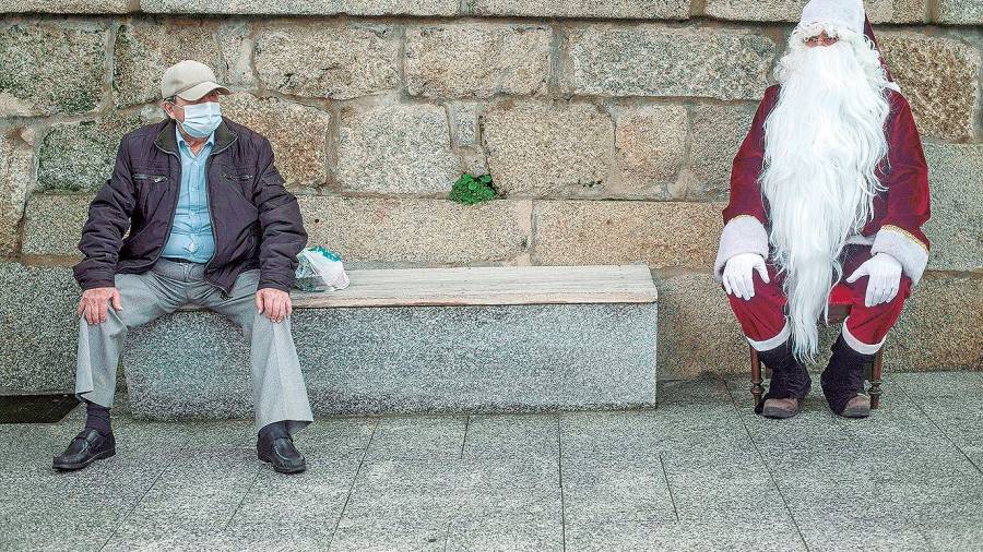 fiestas. Un hombre disfrazado de Papá Noel al lado de un ciudadano con mascarilla (Ourense). Foto: B. Lorenzo