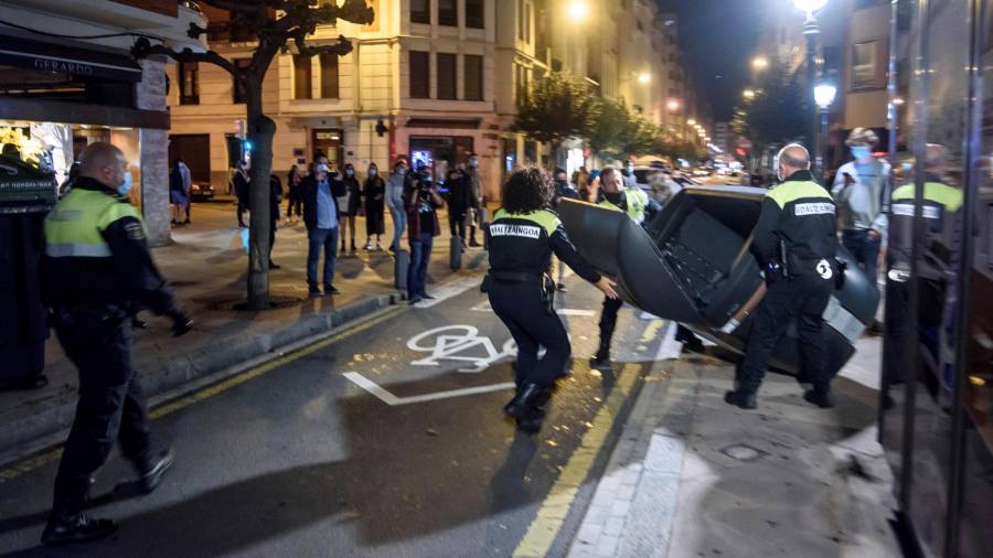 Bilbao, 31/10/2020.- Miembros de la Policía Municipal retiran los contenedores volcados en la calzada por los participantes en las protestas que se han producido la pasada noche en las calles de Bilbao, por las medidas impuestas ante el aumento de contagios de Coronavirus. EFE/JAVIER ZORRILLA.