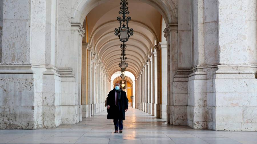 PORTUGAL Un ciudadano luso pasa en solitario por debajo de los arcos en la Plaza del Comercio de Lisboa. Foto: Efe