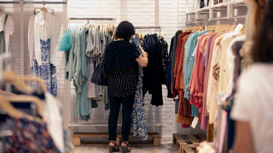 Una mujer busca prendas en un establecimiento textil.