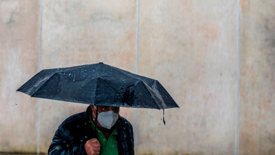 seguro. Un hombre se protege de la lluvia y el virus, entre paraguas y mascarilla (Ourense). Foto: B. Lorenzo 