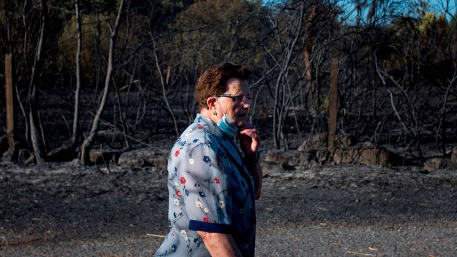 TOÉN (OURENSE), 08/08/2020.- Una mujer ante la superficie calcinada en el incendio forestal que permanece activo en el municipio orensano de Toén. EFE/Brais Lorenzo
