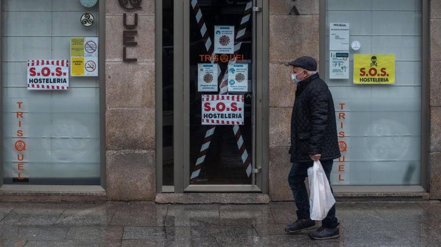 Un hombre camina ayer jueves junto a un bar cerrado en Xinzo de Limia, Ourense, uno de los ayuntamientos con las restricciones más severas de Galicia debido a los malos datos epidemiológicos. EFE/ Brais Lorenzo