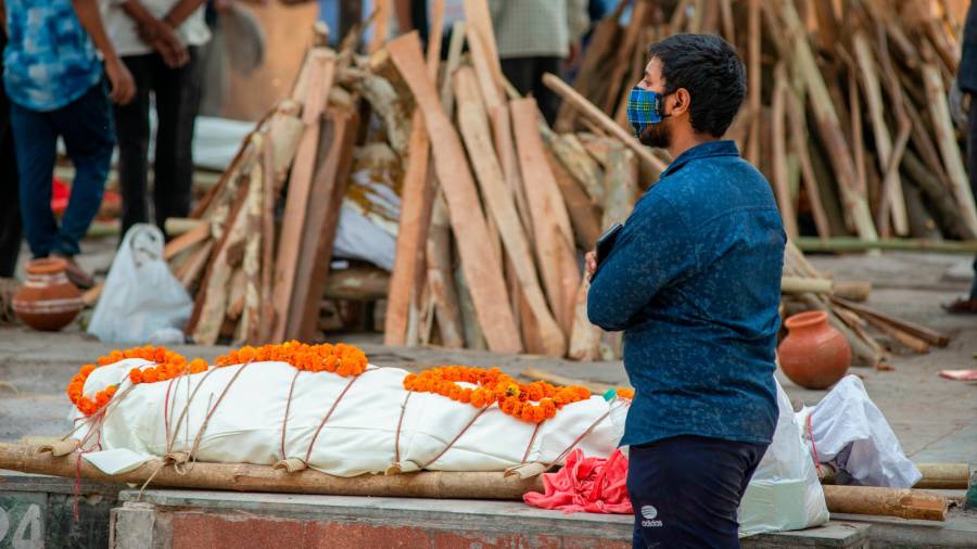 Grandes colas Un hombre esperando junto a un cadáver su turno para ser incinerado, en Nueva Delhi. Foto: Efe