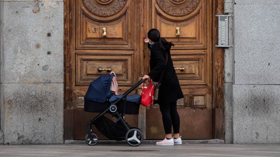 Una mujer ante la entrada de un edificio con un carrito de bebé. Foto: E.P.
