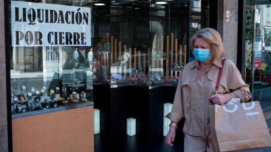 Una mujer pasa ante un comercio que anunciaba el cierre en Ourense. Foto: Efe/B. Lorenzo