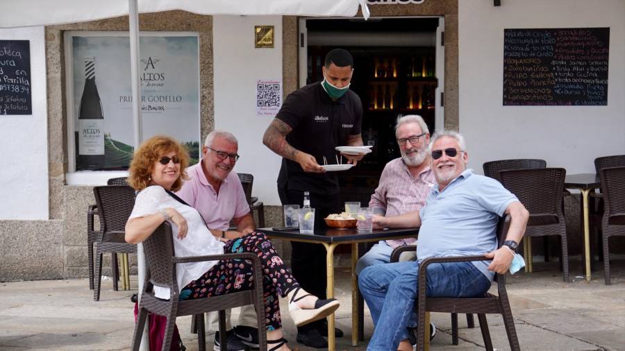 En la foto de archivo, un camarero sirve a un grupo de amigos en una terraza de Santiago. FERNANDO BLANCO